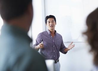 Business man standing in front of a whiteboard looking at two people