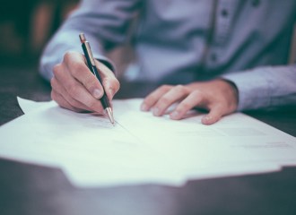 Business man seated at a desk writing on paper